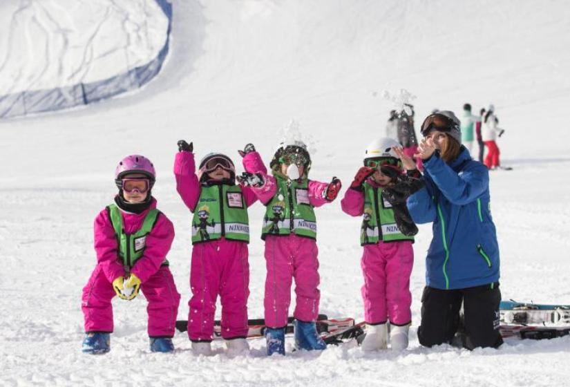 Children in pink suits throwing snow