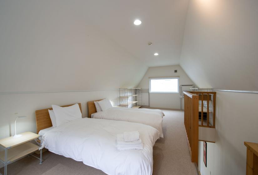 two single beds made up white white linen in the loft area