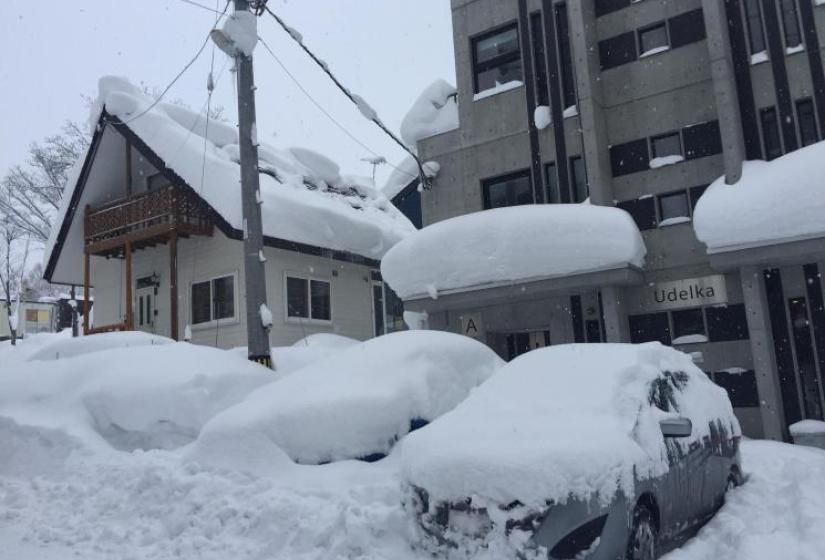 Cars and buildings in Hirafu smothered by snow.