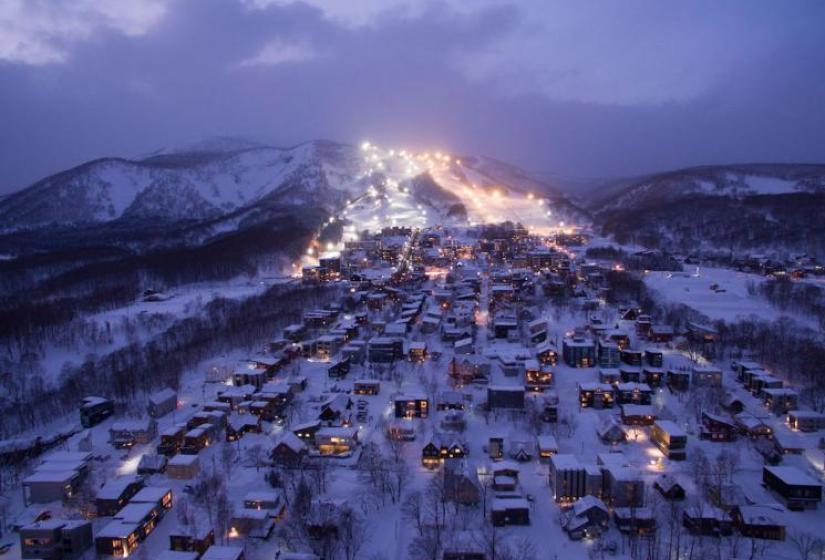 A night time photo of Hirafu village looking up to the lit up ski area