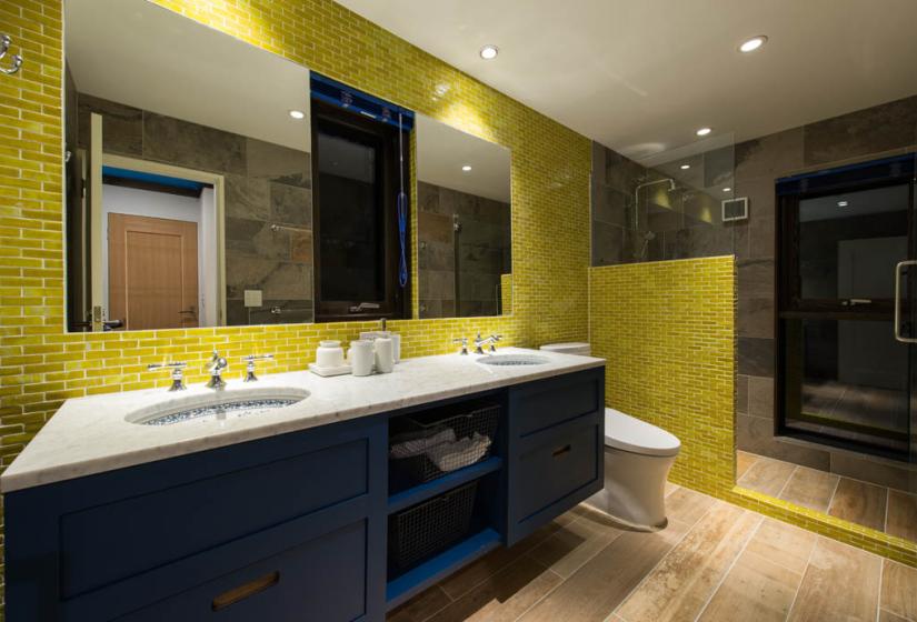 bathroom with twin sinks and shower, yellow tile walls