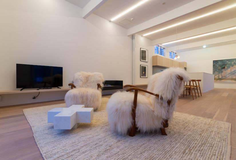 Two chairs with sheepskin rugs beside blue plus shaped coffee table
