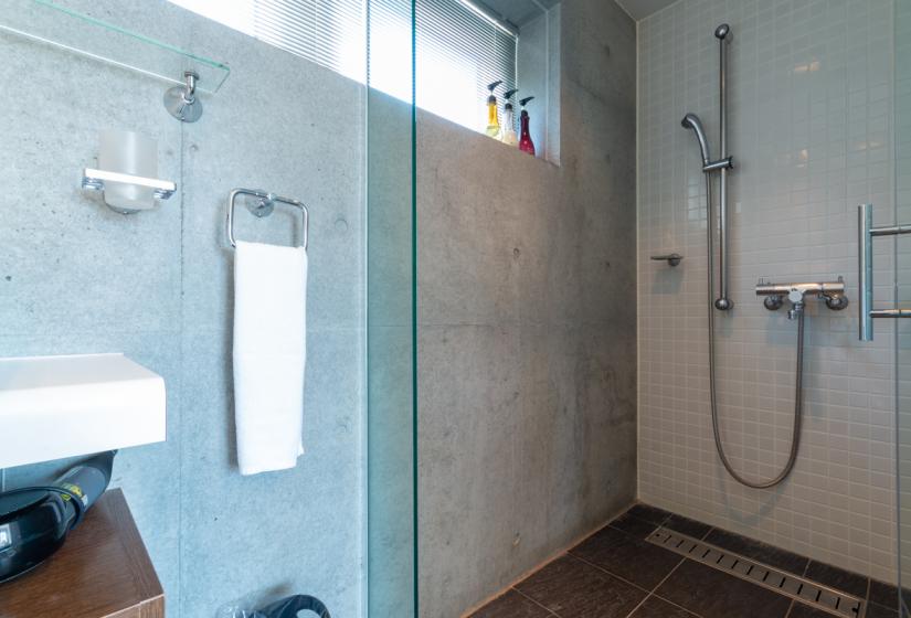 shower with glass door and concrete walls