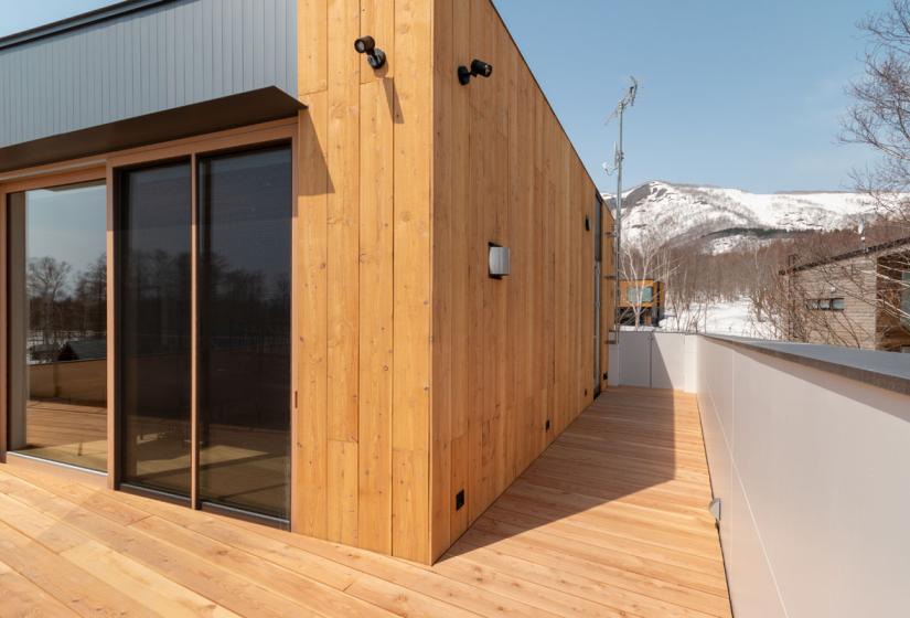 Corner of house with windows and wooden  cladding 