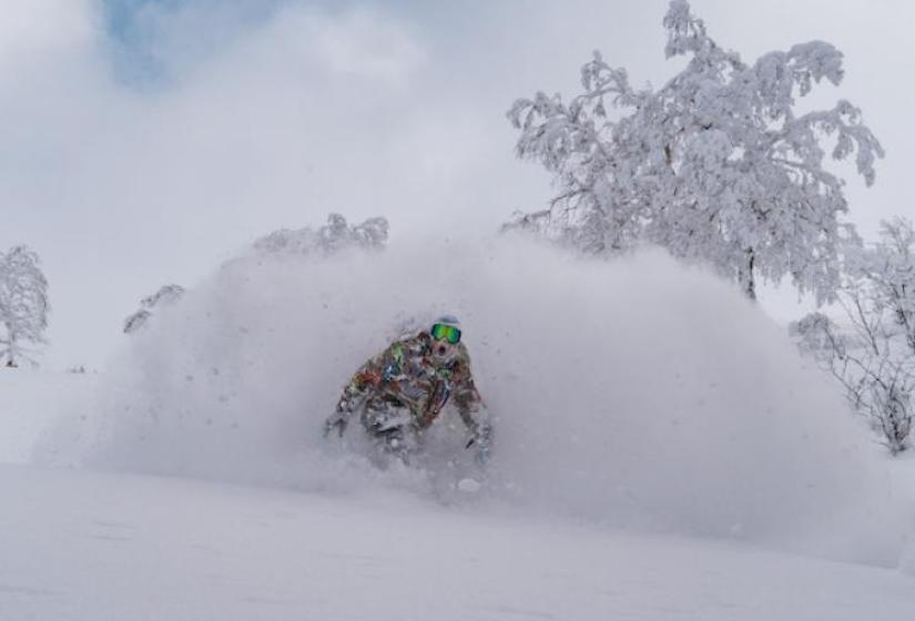 A snowboarder throws up a spray of powder snow