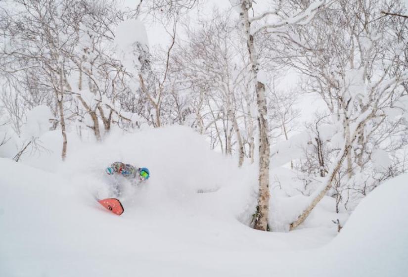 A snowboarder makes a deep powder turn