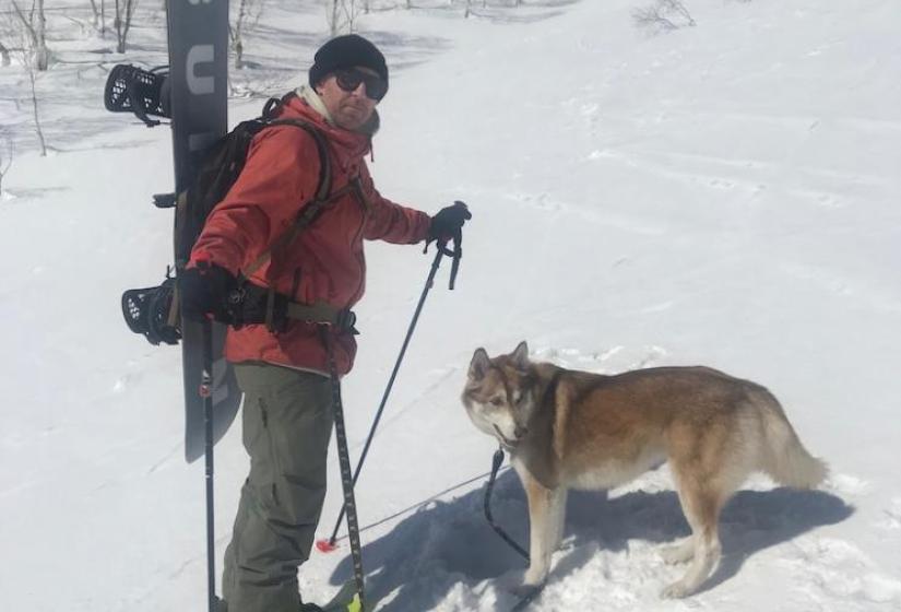 Man with snowboard back pack with dog