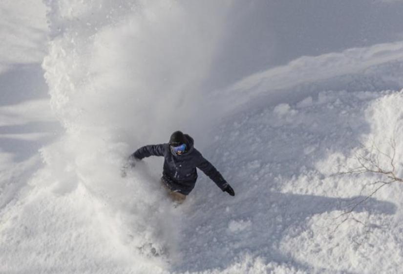 A snowboarder makes a deep turn.