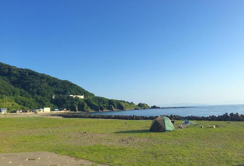 A tent pitched on green grass by the sea