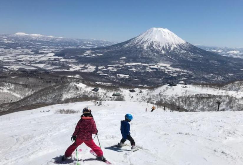 Kids skiing in Hirafu Children ski down a slope