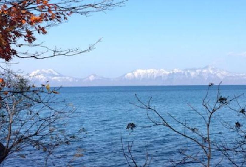 A lake and mountain scene framed by autumn leaves