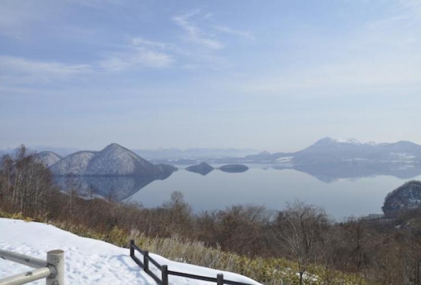 A glassy Lake Toya A mirror calm lake with triangular islands and their mirror image