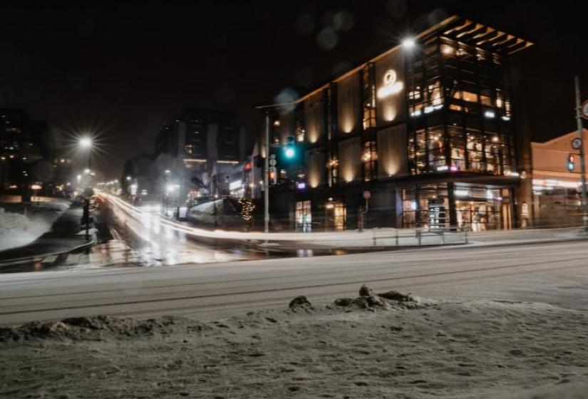Odin Place A snowy road with 3 story lit up building to the right