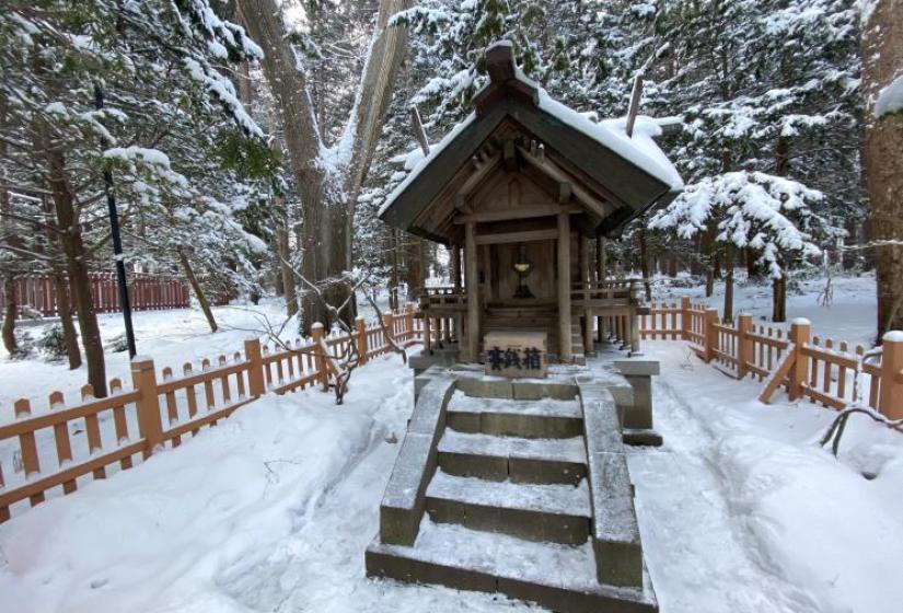 A small Budhist shrine amongst trees and snow