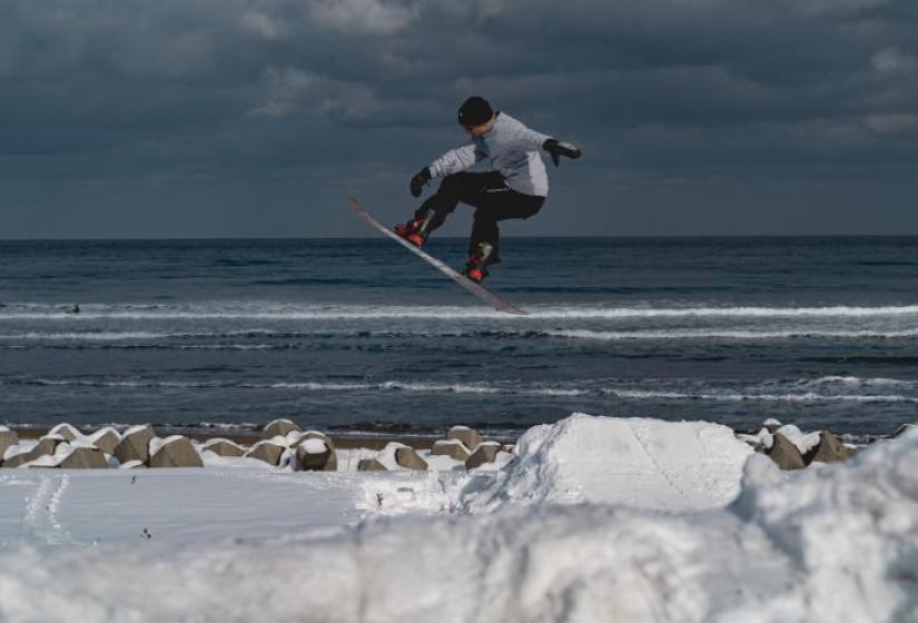 A snowboarder jumping near the see