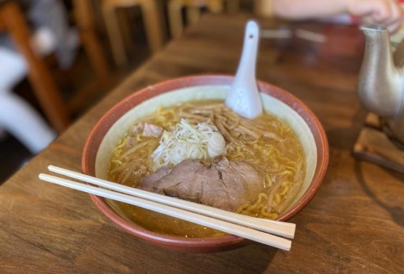 A bowl of ramen noodles with chopsticks resting on the bowl edge