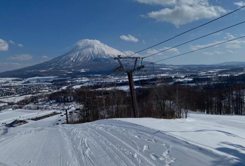 Blue skies and great skiing A lift tower and ski slope with Mt Yotei in the background
