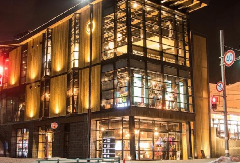 Odin Place Hirafu An illuminated 3 story building on the corner of a snowy street