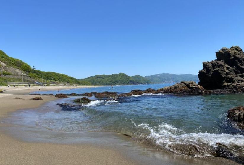 A tiny wave breaks in front of a rock promontory 