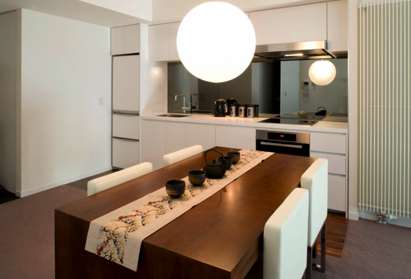 dining table with tea set, kitchen stove and counter in background