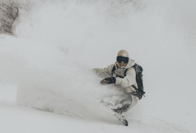 A snowboarder digging a deep powder turn