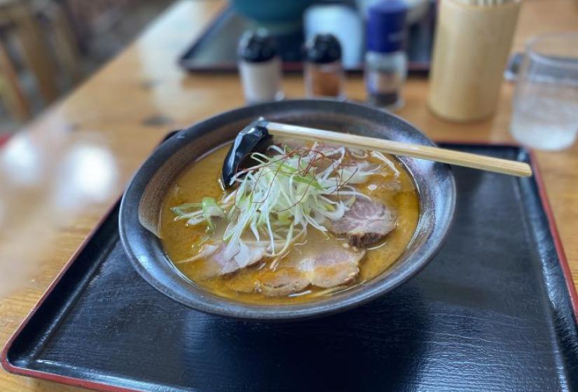 A bowl of ramen noodles with a wooden spoon on top