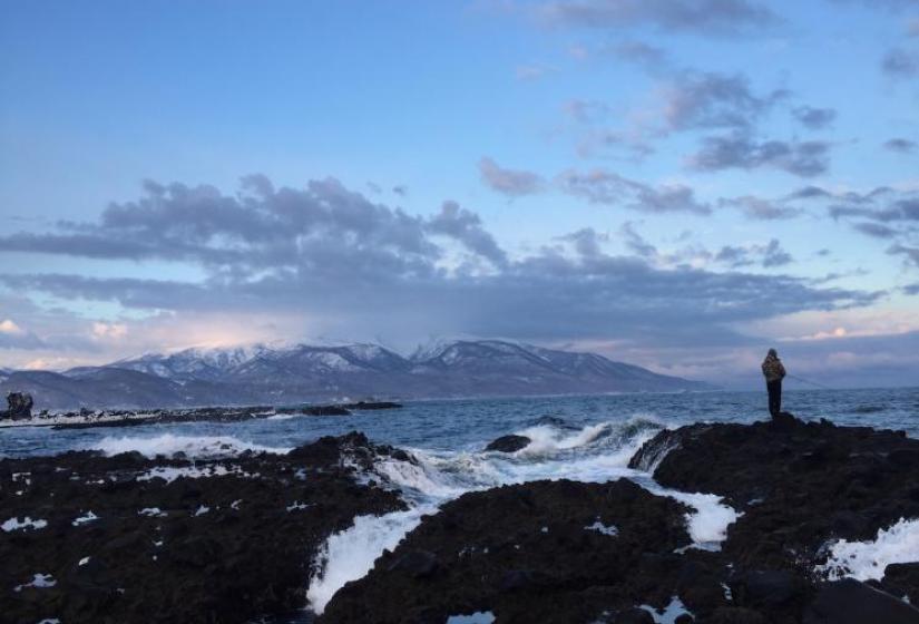 A man fishing with snow covered peak in the back ground