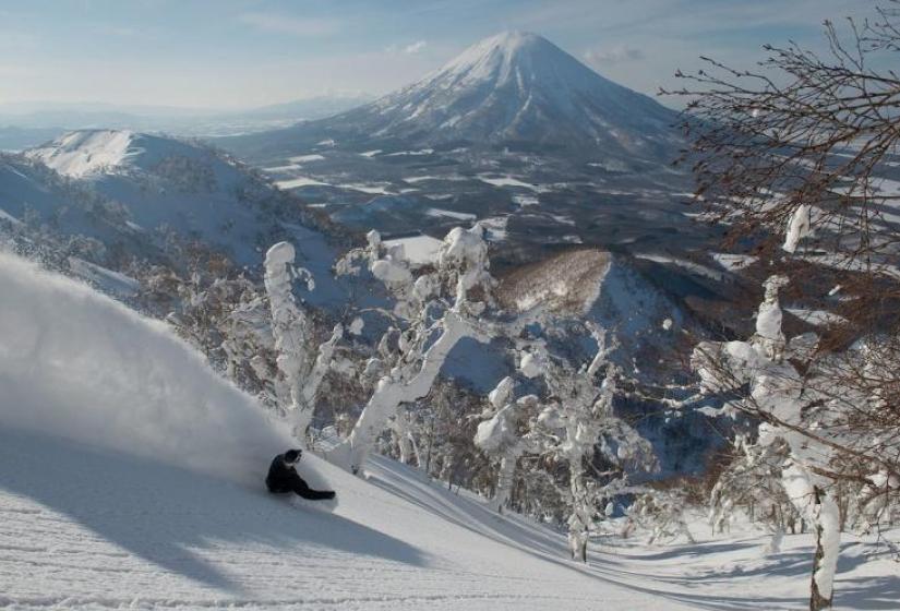 A snowboarder makes a turn amid a snowy backdrop