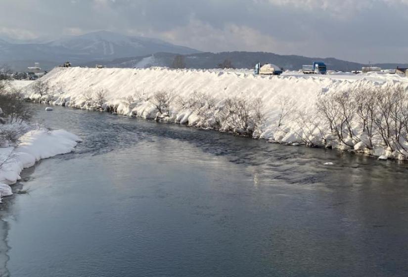 Trucks dumping snow near a river