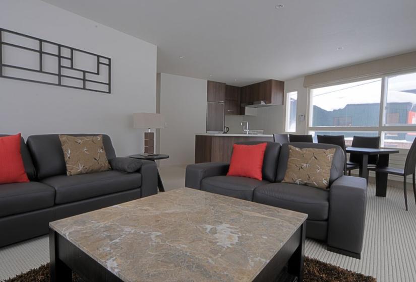 living area with stone coffee table and black leather couches