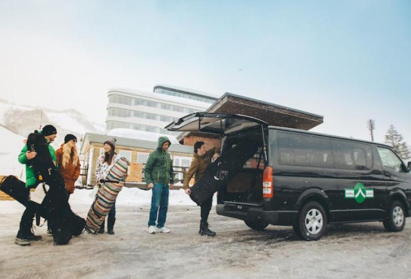 Door to door service A driver loads a van while guests wait