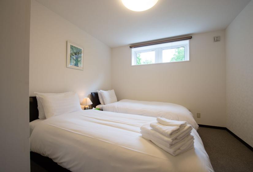 2 single beds made up with white linen and folded towels on top