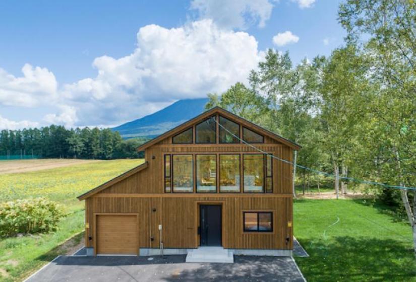 Yoteiyama House A large wooded house with double pitched roof and blue skies behind