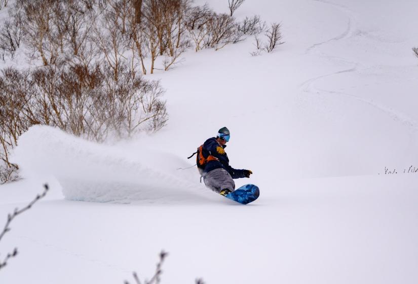 A snowboarder makes a deep turn in the powder