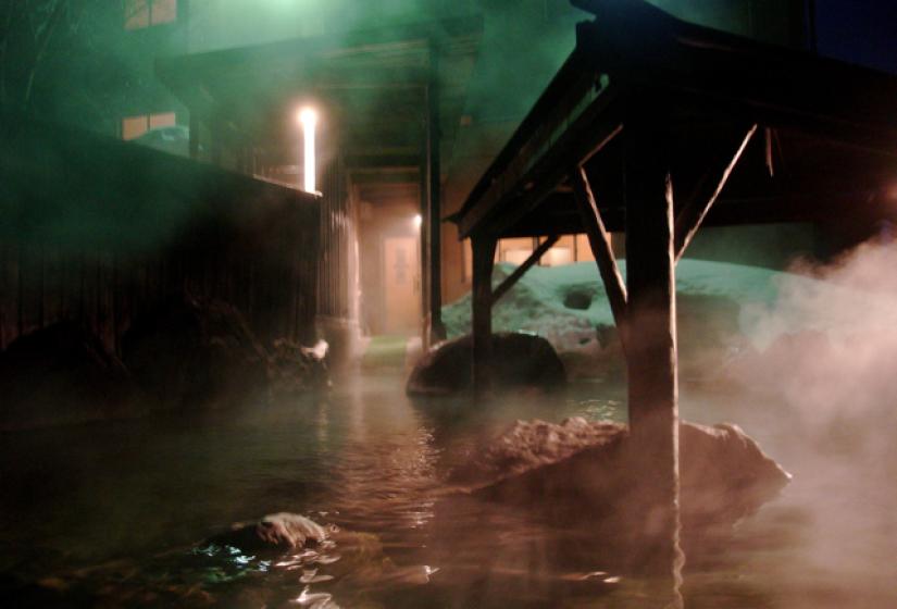 A steaming outdoor hot spring at night