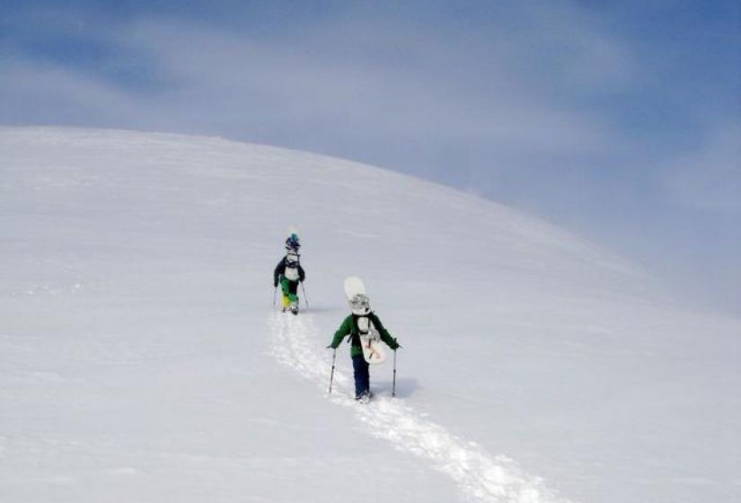 The snow dreams are made of. Snowboarders hiking toward to snowy summit of Mt Annupuri
