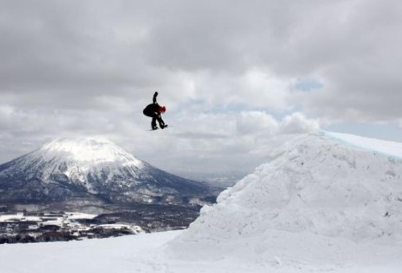 A snowboarding spinning off a large jump
