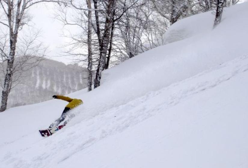 A snowboarder makes a deep turn in the powder.