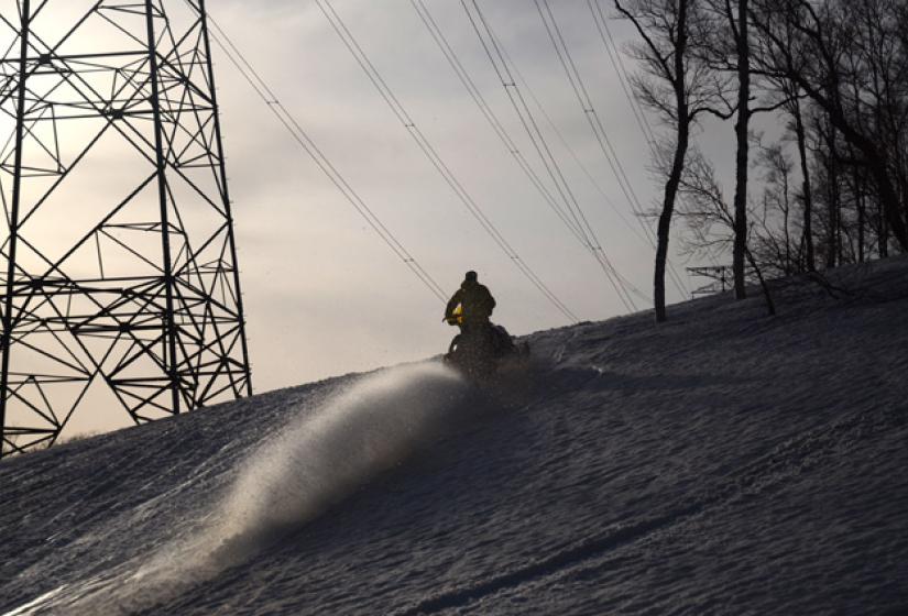 Snowmobiling in the spring A snowmobile below large power pylons.