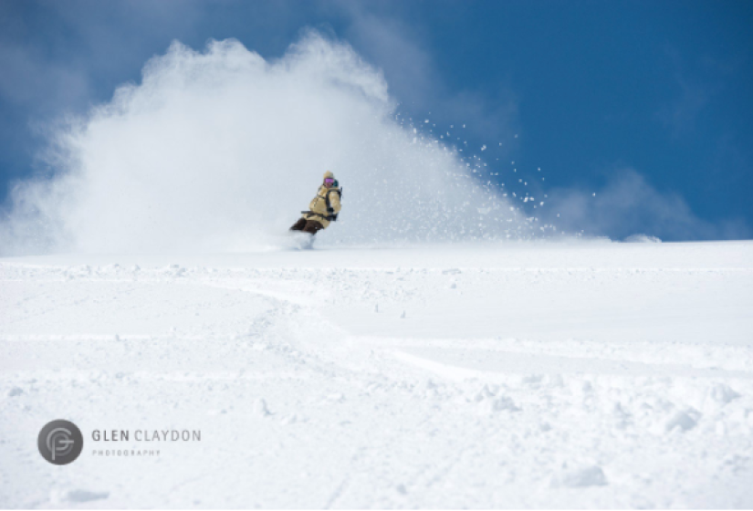 A snowboarder makes a deep turn in the powder