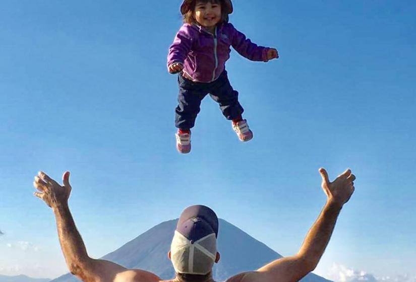 Trevor throwing his daughter in the air with Mount Yotei in the back ground.