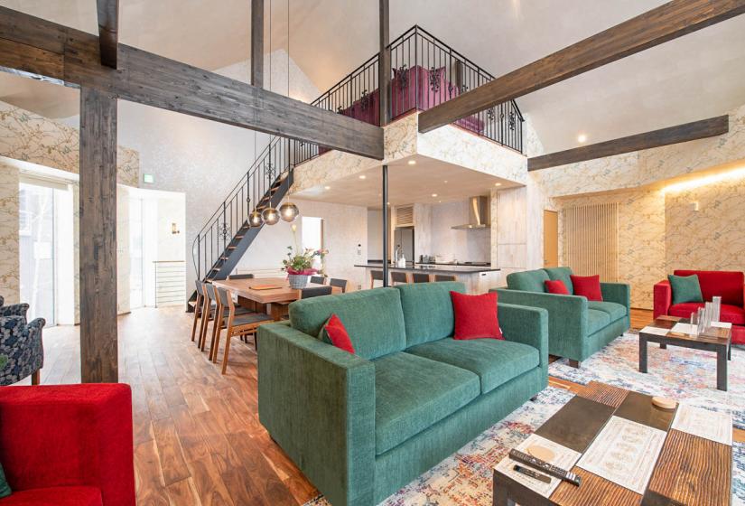 Green sofas with red cushions in floral wallpapered living room