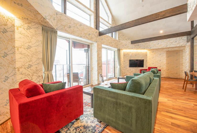 red chair and green sofa in floral wallpapered living room