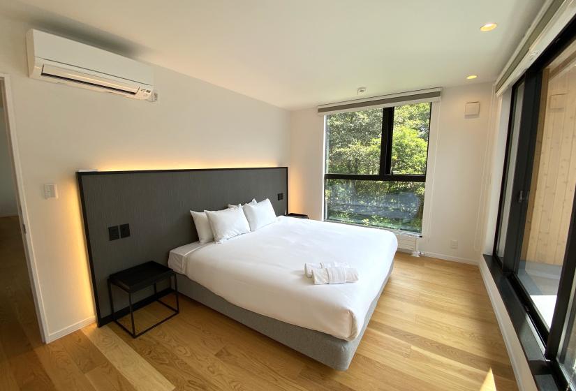 Kihaku master A double bed with back lit head board and greenery visible through the windows.