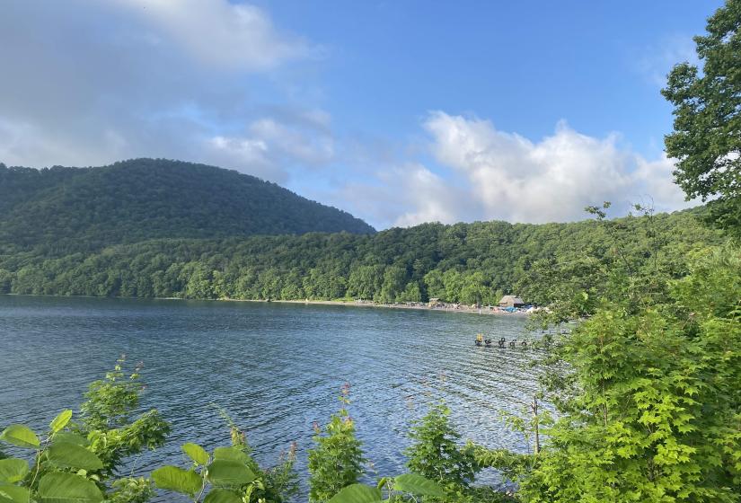 A lake surrounded by green forests and a small wharf in the foreground.