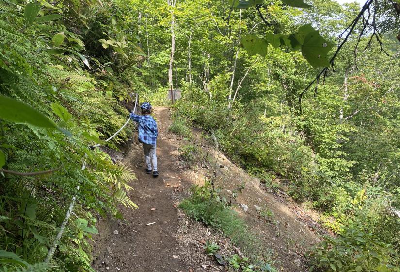 A young boy holds a rope while traversing a steep slope.