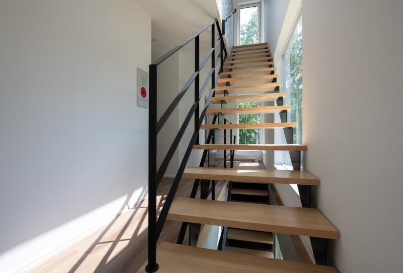 A wooden stair case with black handrail
