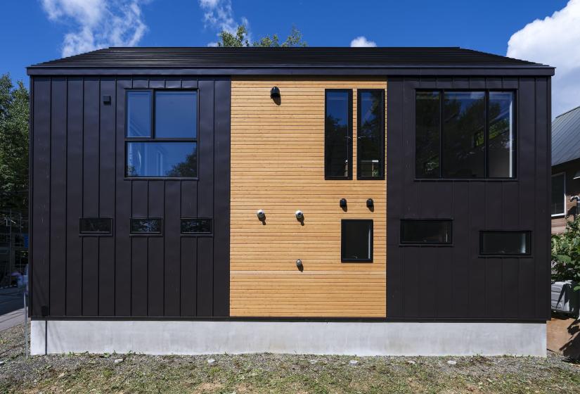 A two story house with black and wood coloured cladding