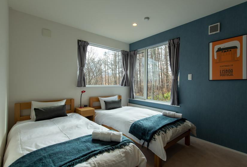 2 single beds with blue throws and blue wall to the right