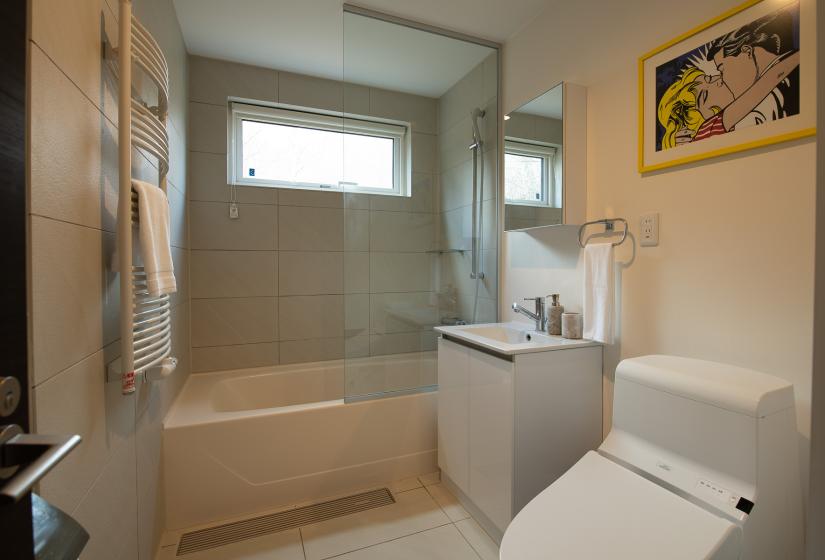 A bathroom with tiled wall, toilet and basin.